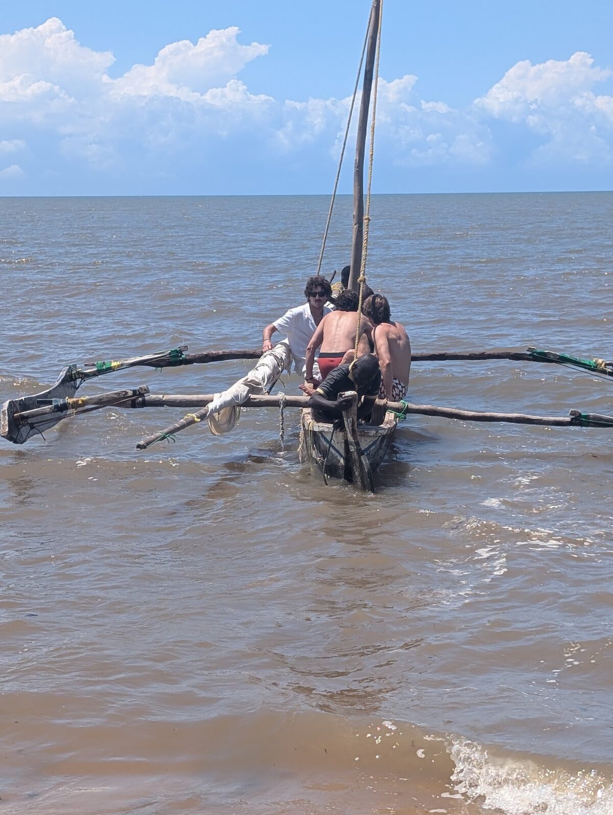 Guests boarding the outrigger from the shallows, sail up