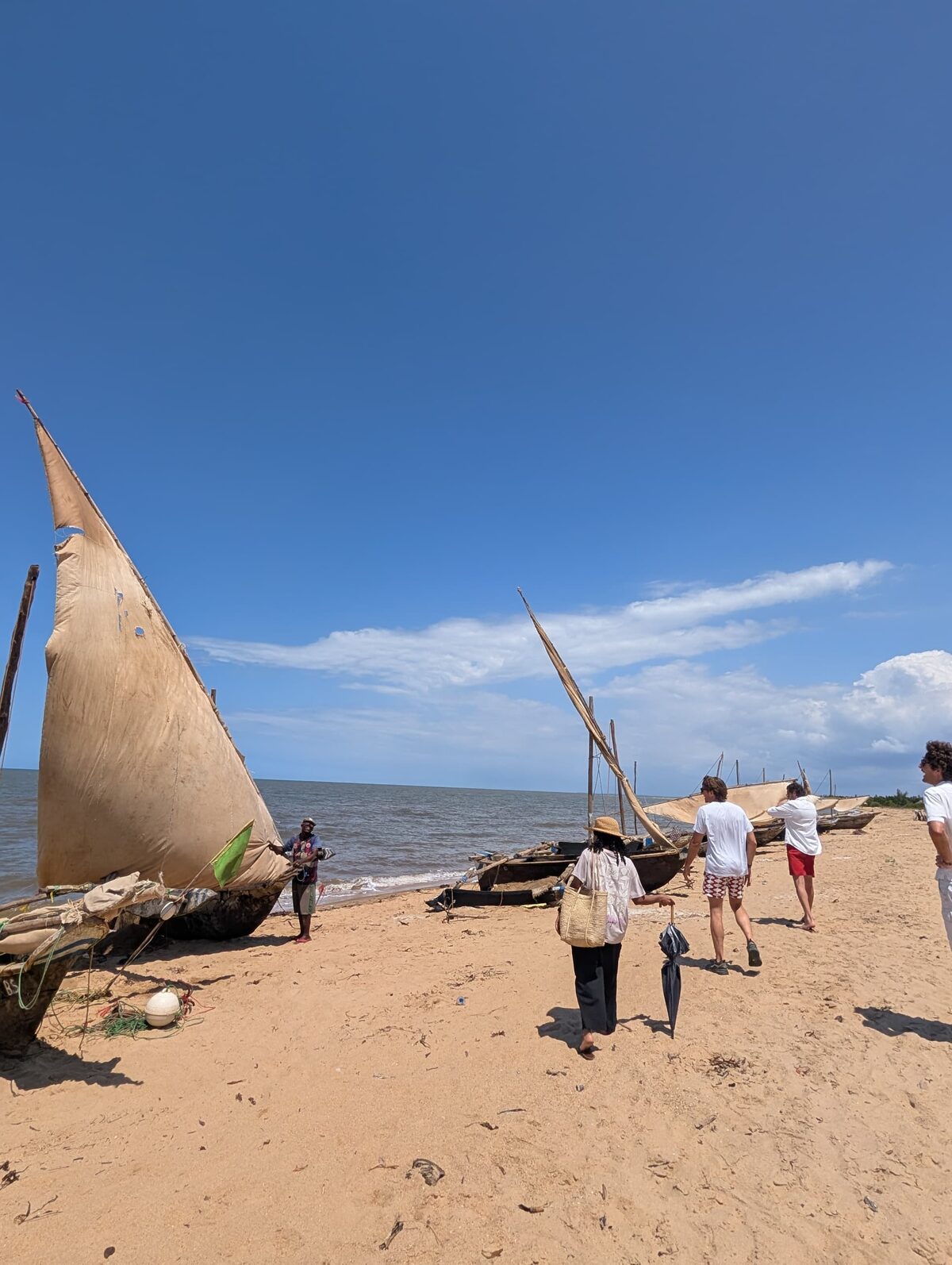 Traditional dhows drawn up on the sand at Saadani, guests walking along the shore