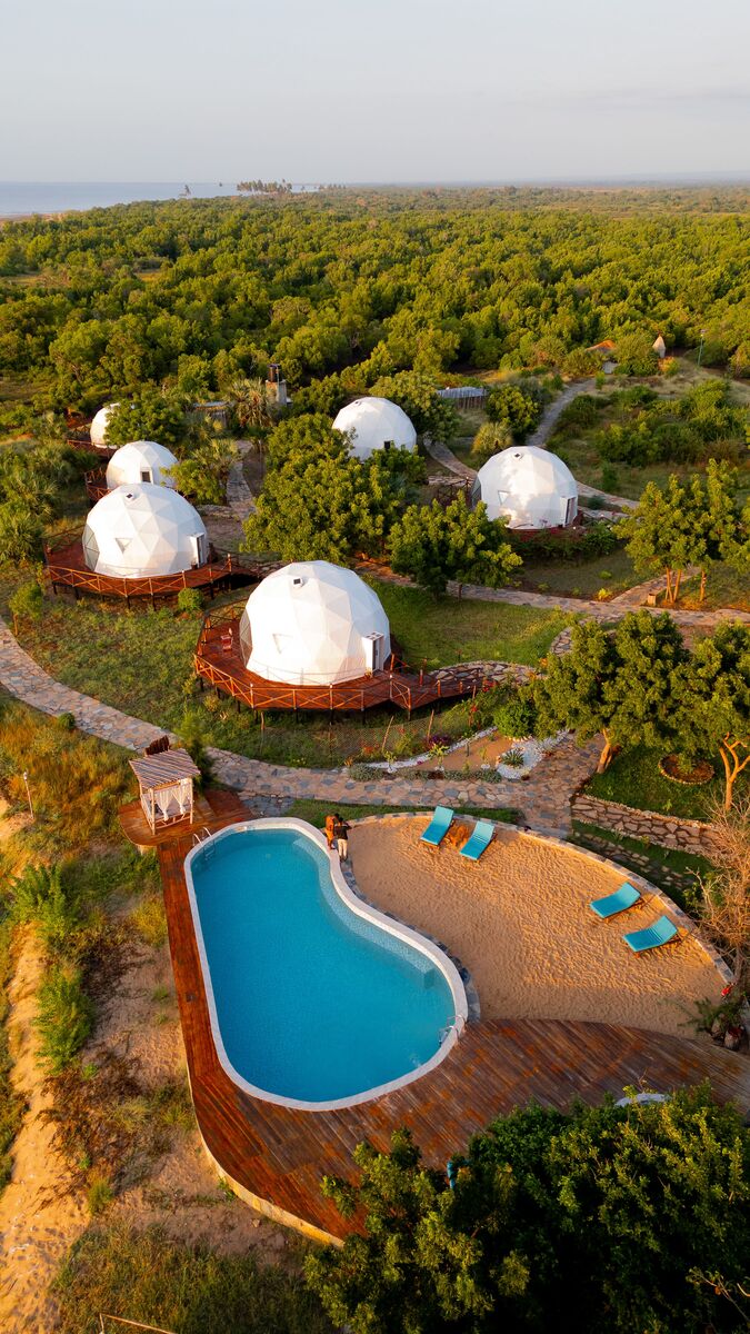 The domes from outside — The tented domes on their platforms, among the palms and facing the ocean.