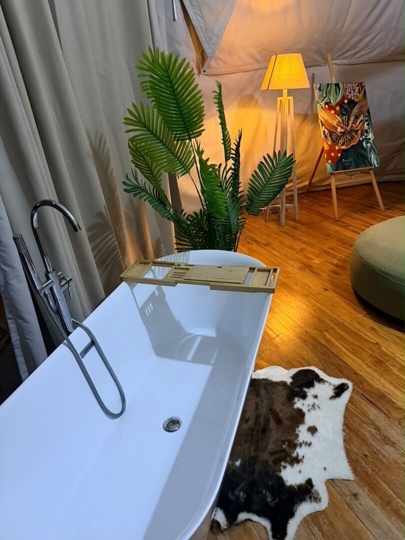 The freestanding bath in the Honey Suite, with a painted canvas and a floor lamp behind it