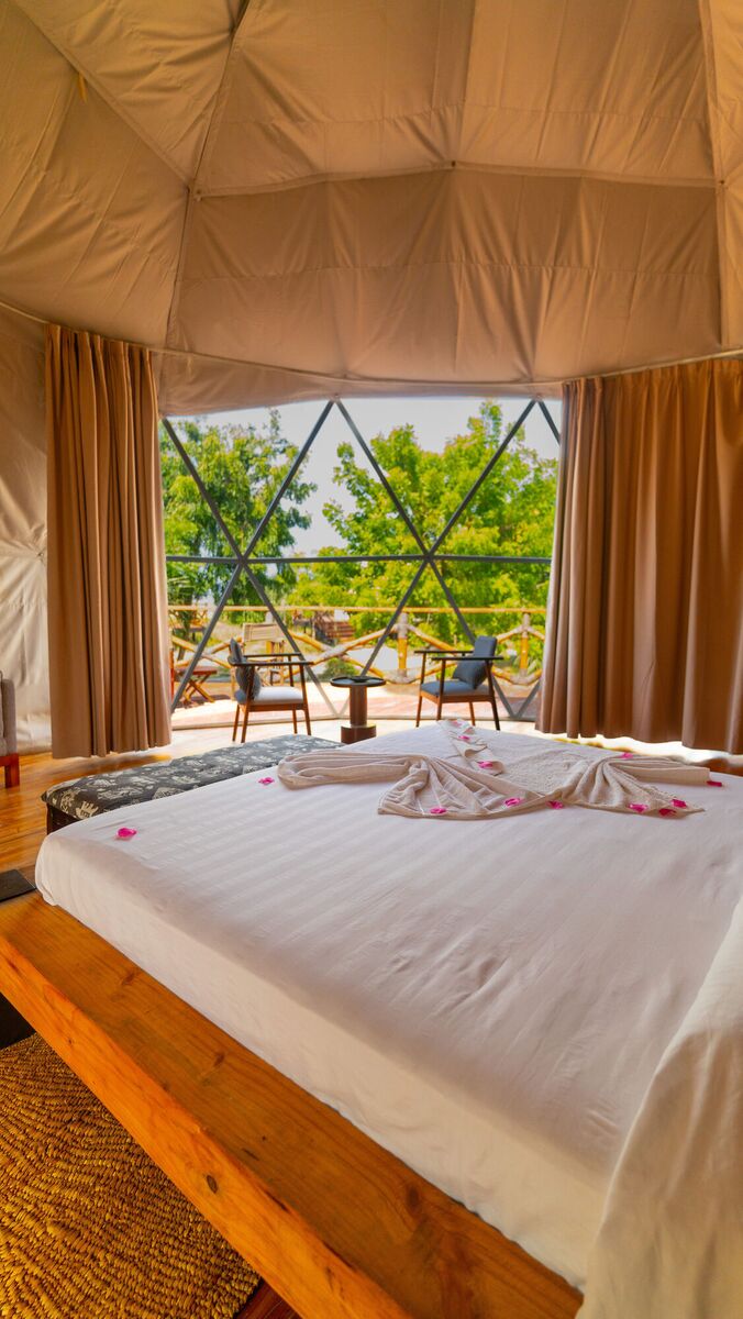 Inside a Family Garden dome at Cterra Saadani, with the loft rail and the bench at the foot of the bed