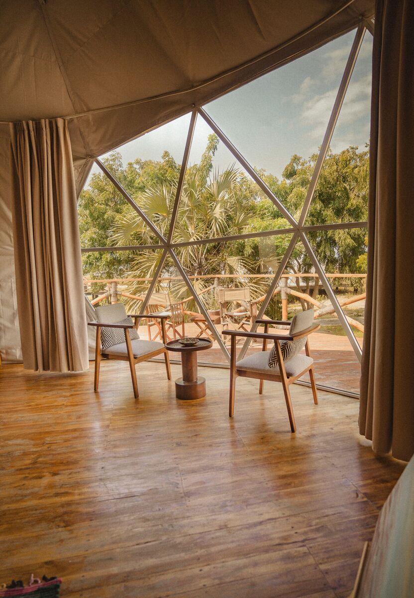 Inside a Family Garden dome at Cterra Saadani, with the loft rail and the bench at the foot of the bed