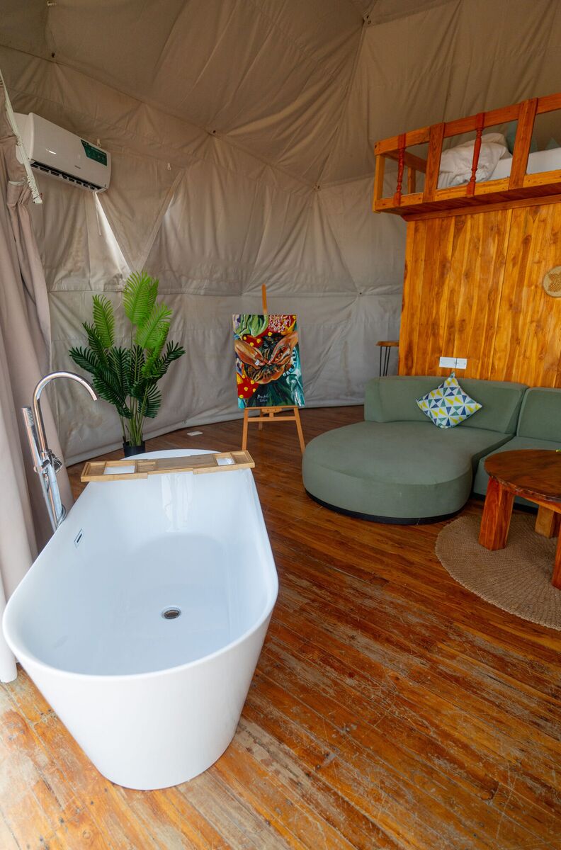 The Honey Suite at Cterra Saadani, with the green sofa and the freestanding bath