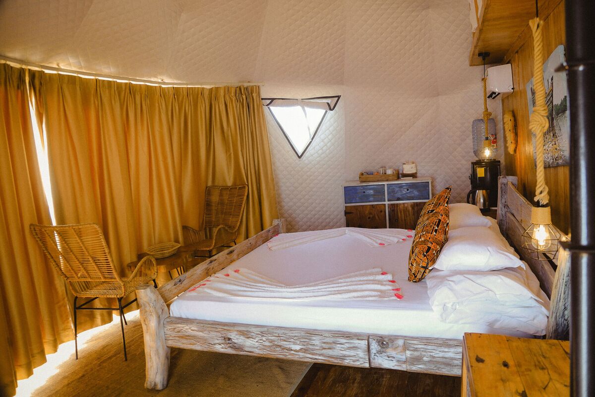 Inside a Standard tent at Cterra Saadani, with the timber wall and the driftwood bed