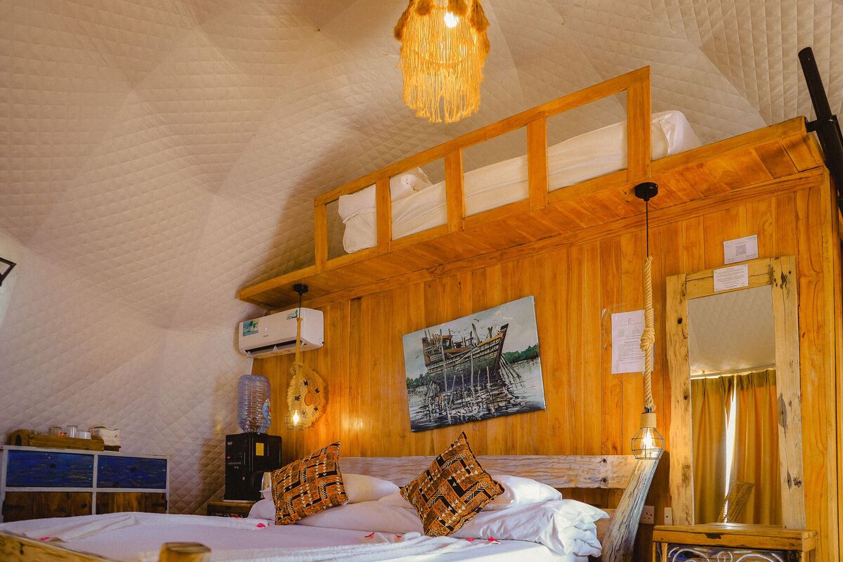 Inside a Standard tent at Cterra Saadani, with the timber wall and the driftwood bed