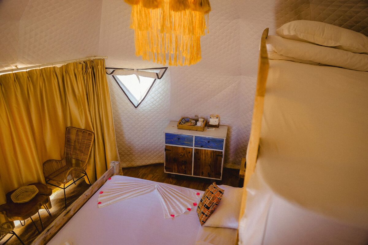 Inside a Standard tent at Cterra Saadani, with the timber wall and the driftwood bed