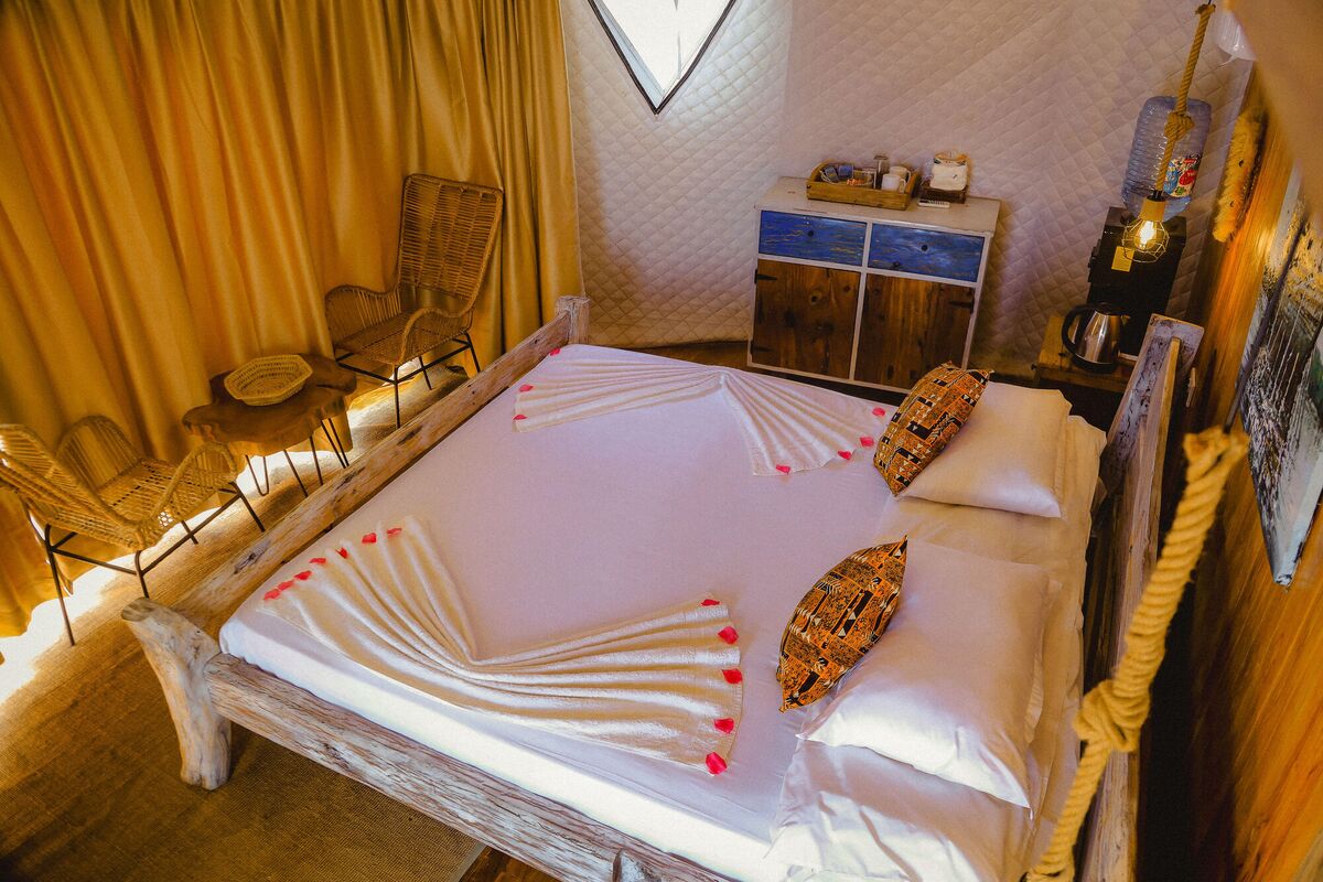 Inside a Standard tent at Cterra Saadani, with the timber wall and the driftwood bed