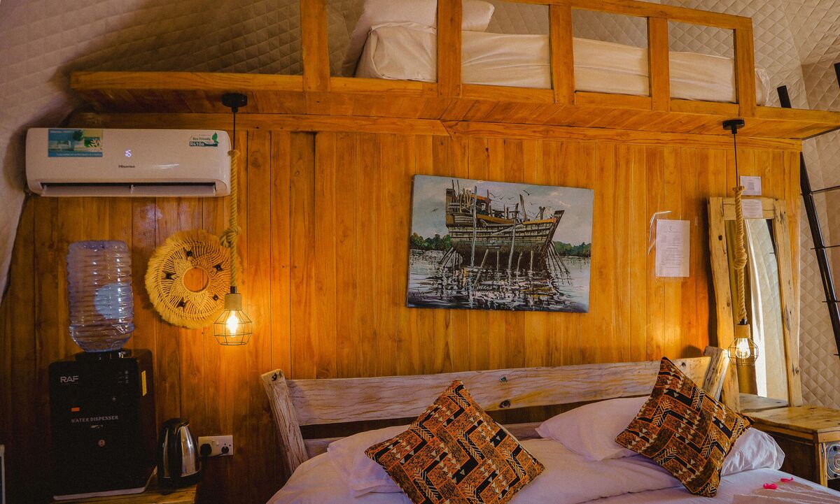 Inside a Standard tent at Cterra Saadani, with the timber wall and the driftwood bed