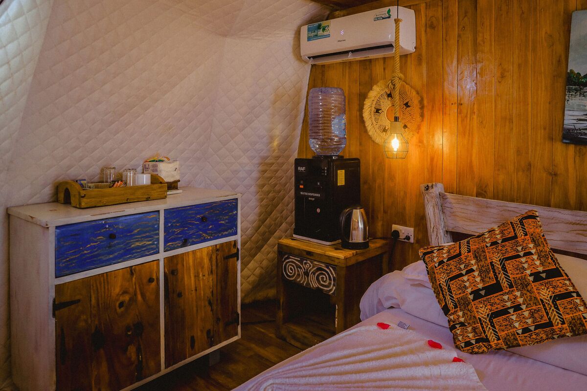 Inside a Standard tent at Cterra Saadani, with the timber wall and the driftwood bed