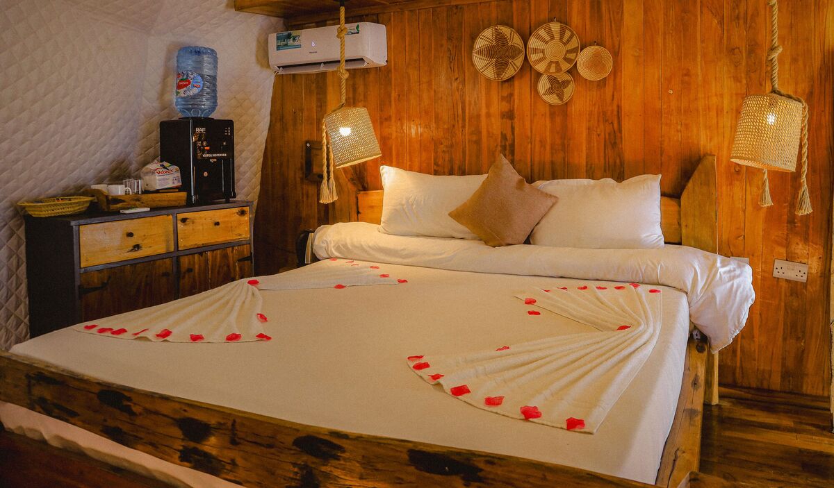 Inside a Standard tent at Cterra Saadani, with the timber wall and the driftwood bed