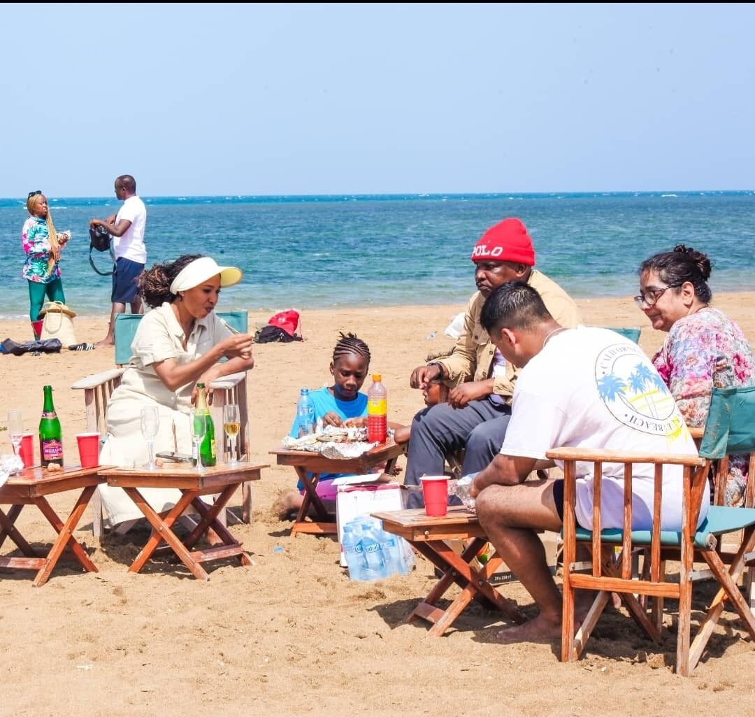 Lunch laid out on low tables on the sand at Mafui, with guests eating by the water