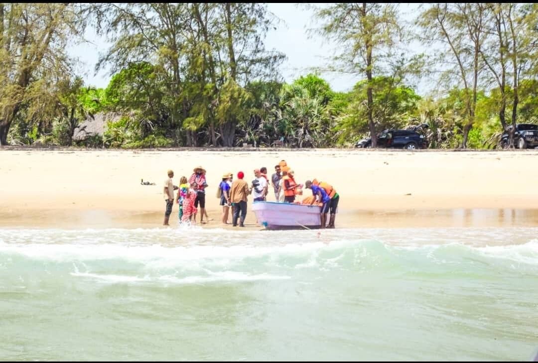 A group stepping ashore from a small boat onto the sandbank at Mafui