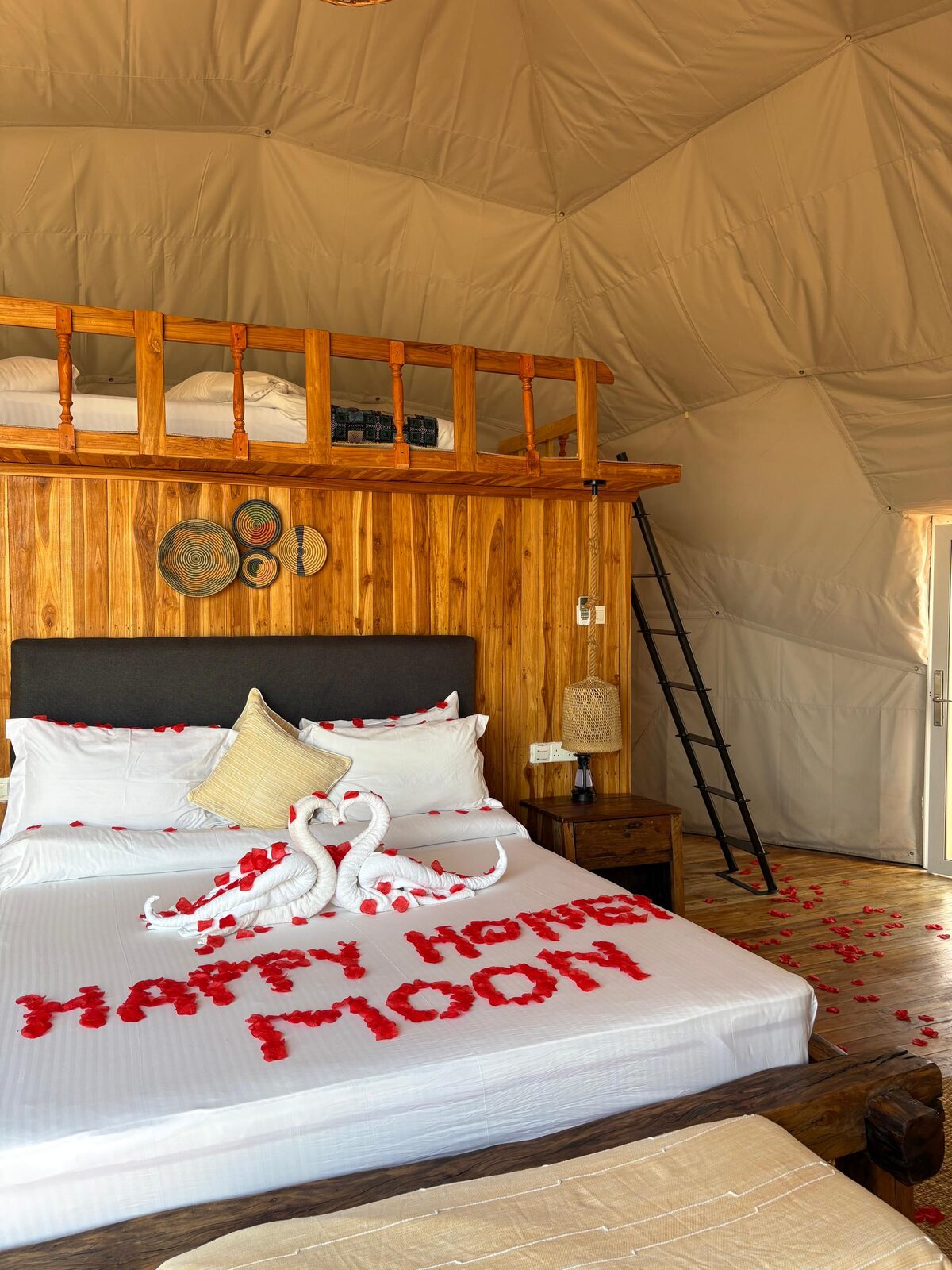 «Happy honeymoon» written in rose petals on the bed, under the sleeping loft