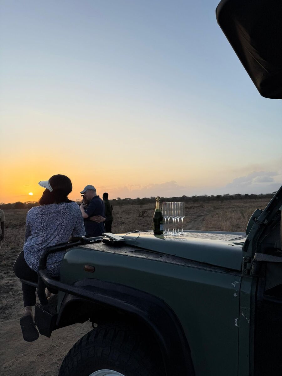 Glasses and a bottle set out on the bonnet of the safari vehicle as the sun goes down