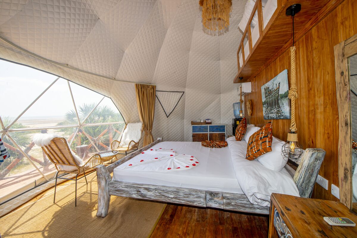 A dome tent interior at Cterra Saadani, the bed facing the glazed wall