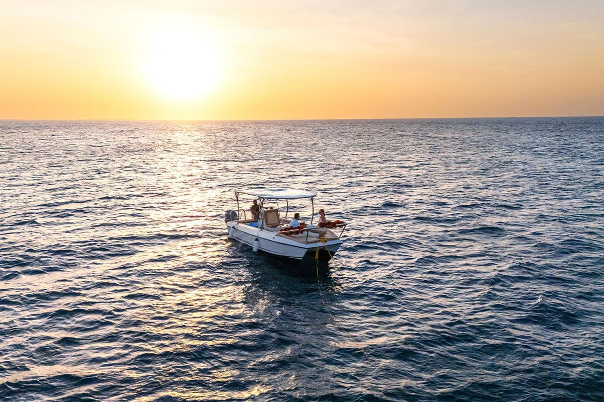 The boat at anchor with the sun low over the water