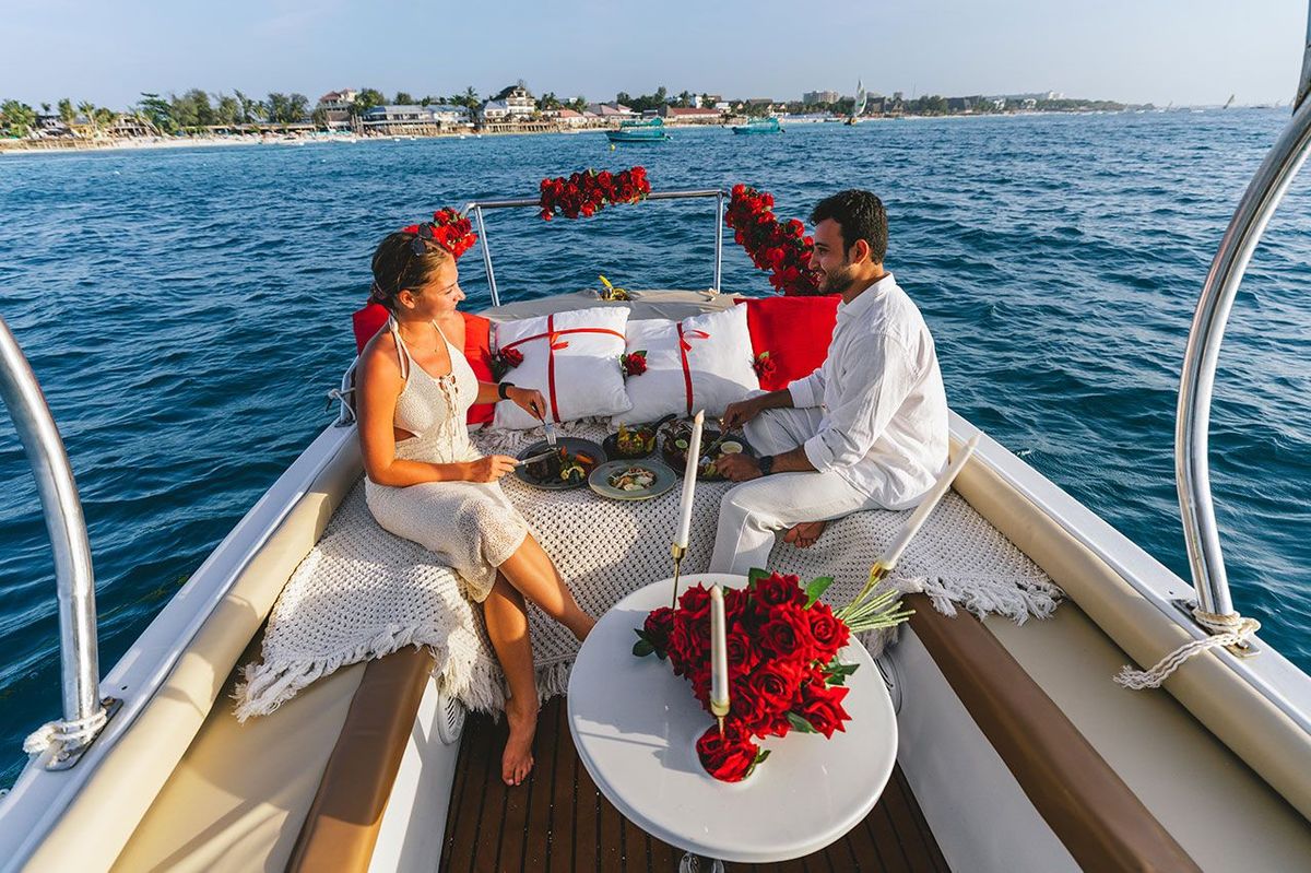 Two guests eating at a low table on the deck, cushions and roses around them