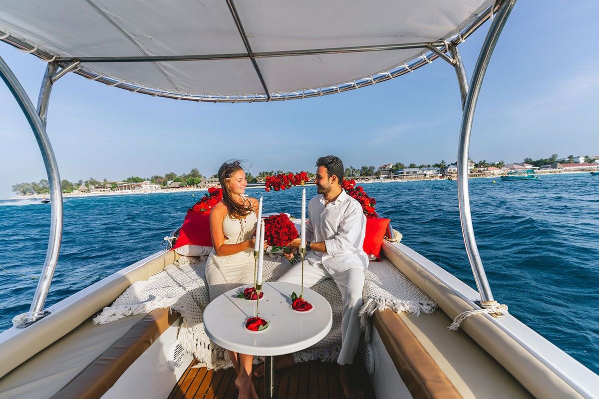 A table laid for two on the deck, roses along the rail and the coast behind